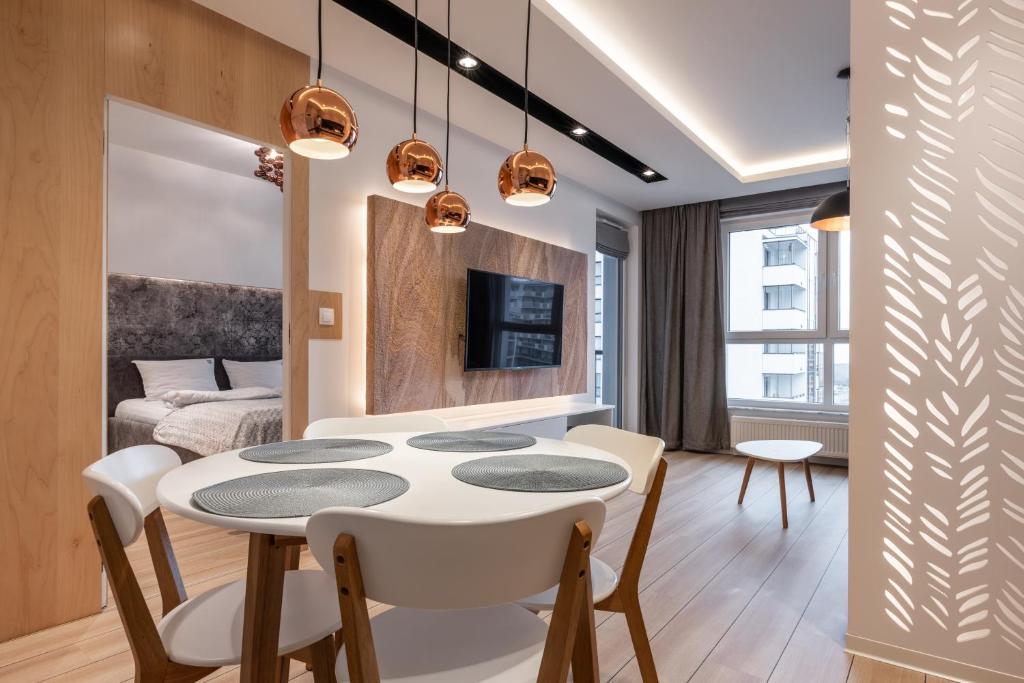 格但斯克Sweda Apartments Gdańsk Seaside的餐厅和客厅配有白色桌椅