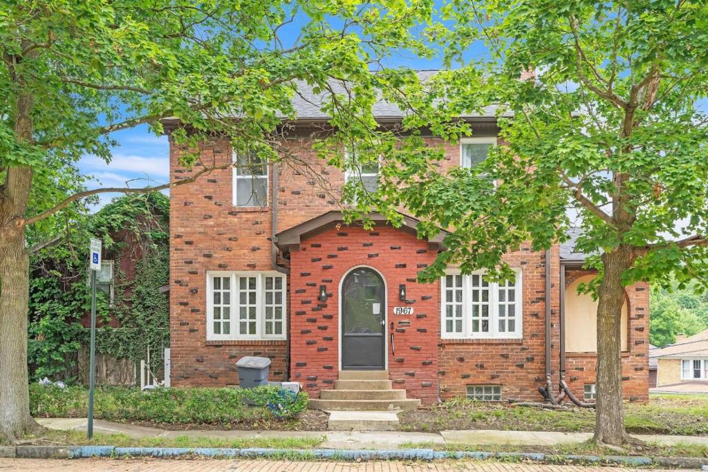 a brick house with trees in front of it at Where Classic Charm Meets Modern Serenity in Pittsburgh