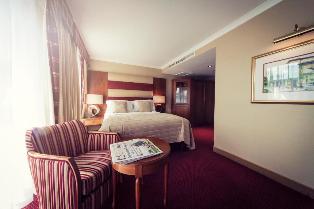 a hotel room with a bed and a chair and a table at Carlton George Hotel in Glasgow