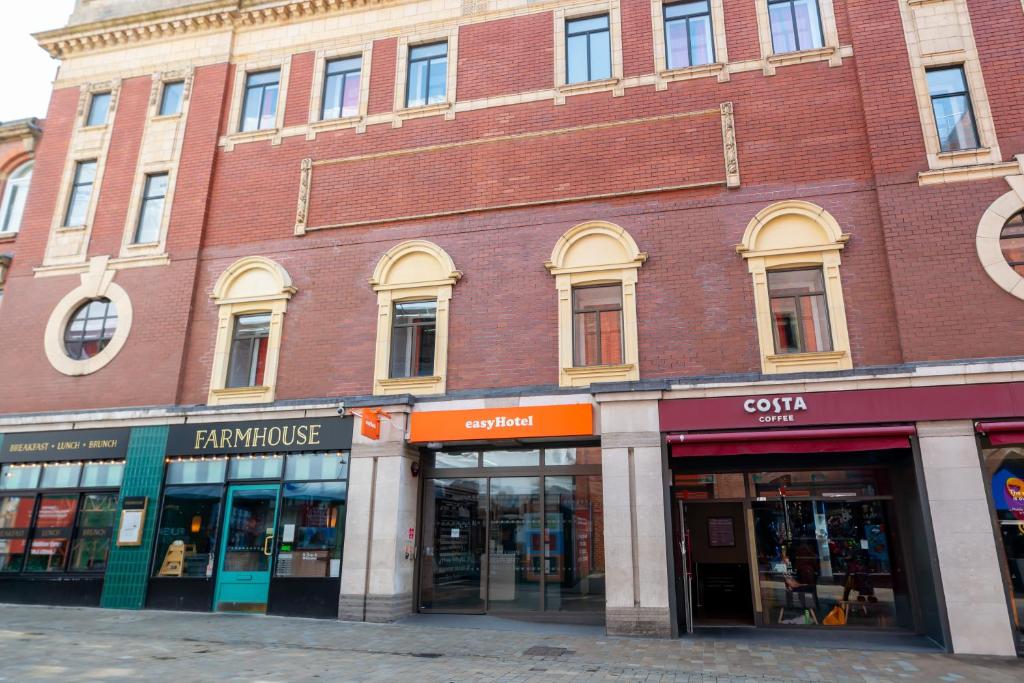 un grande edificio in mattoni su una strada con negozi di easyHotel Leeds a Leeds