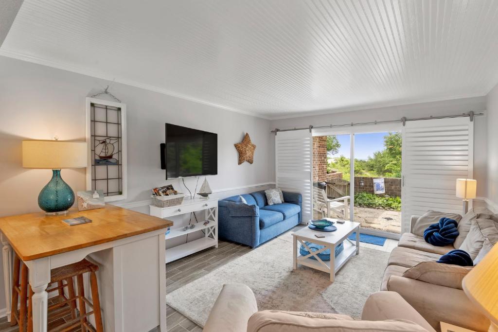 Una sala de estar con un sofá azul y un televisor. en Villas J2, en Nags Head