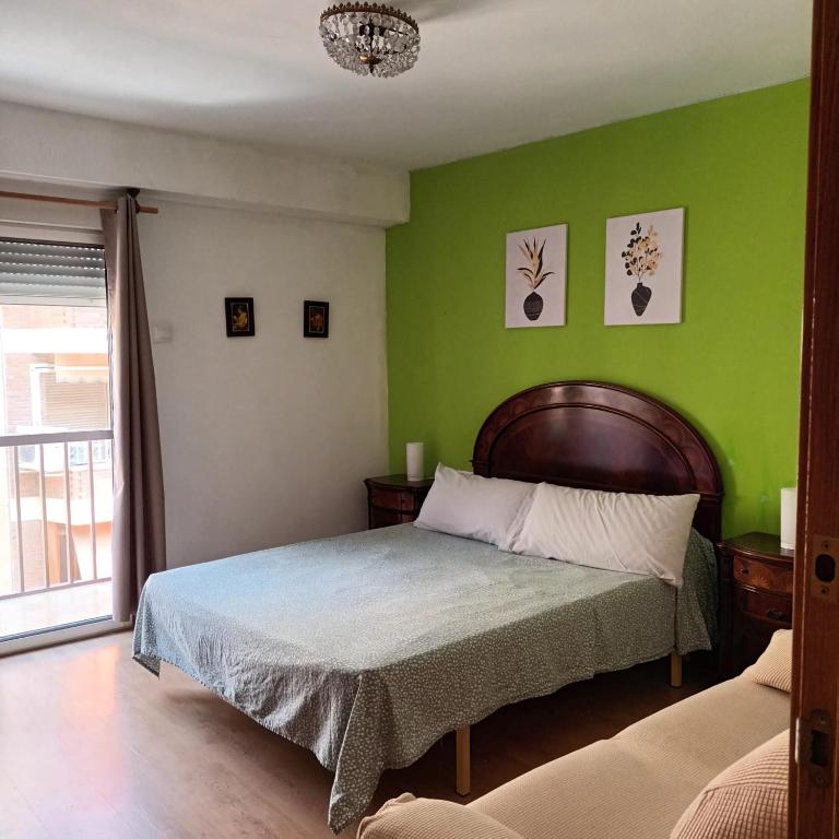 a bedroom with a bed with a green wall at Habitación en centro de Alicante in Alicante