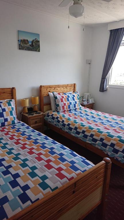 a bedroom with two beds with colorful blankets at Fairways Guest House in Newquay