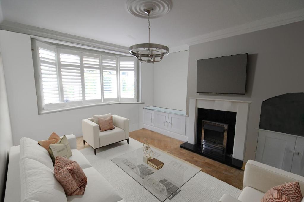 een woonkamer met een witte bank en een open haard bij Stunning Caterham 4 bedroom home in Kenley