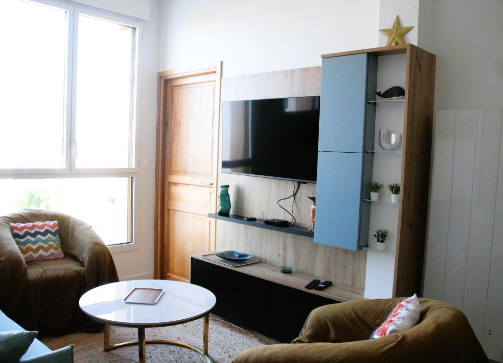 un soggiorno con una TV, un divano e un tavolo di Les Pieds dans l'Eau a Roscoff