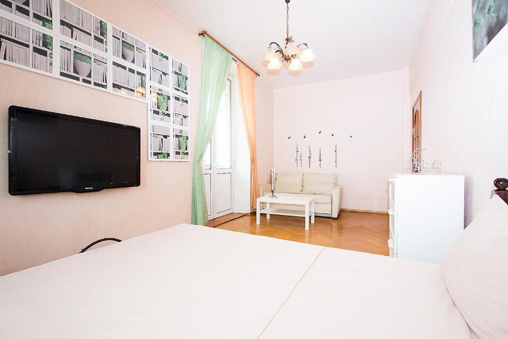 a bedroom with a white bed and a flat screen tv at Apartlux on Karetnyy Ryad in Moscow