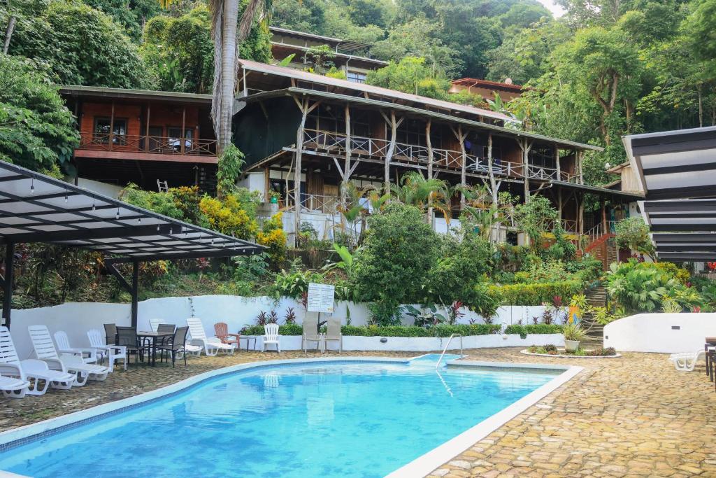 a hotel with a swimming pool in front of a building at Hostel Plinio in Manuel Antonio