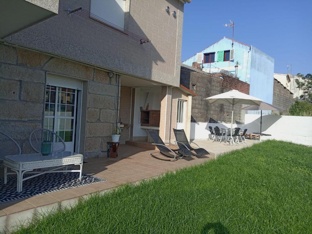 patio z krzesłami i parasolem obok budynku w obiekcie Casa O Vento w mieście O Grove
