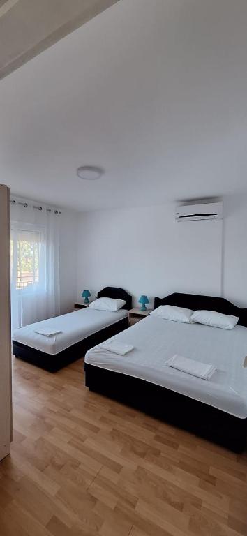 two beds in a room with wooden floors at Apartments Aurora in Bar