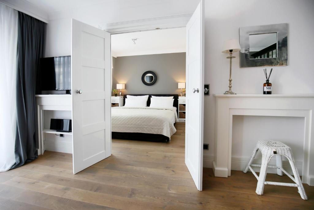 a white bedroom with a bed and a mirror at Das Windhuk in Westerland