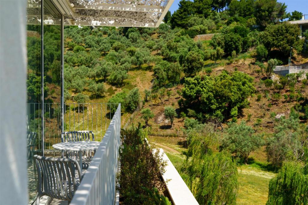 a balcony with chairs and a table on a hill at Radisson Resort Plaza Skiathos in Kanapitsa