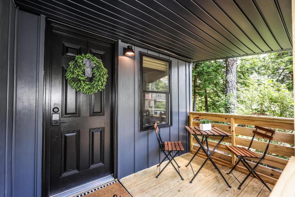 a porch with a black door and a table and chairs at BrookHaus - Modern Cabin Stay at Harvard Brook in Lincoln