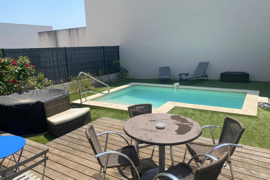 a patio with a table and chairs next to a pool at Pleasant modern house t4 airco pool jacuzzi parking in Juvignac