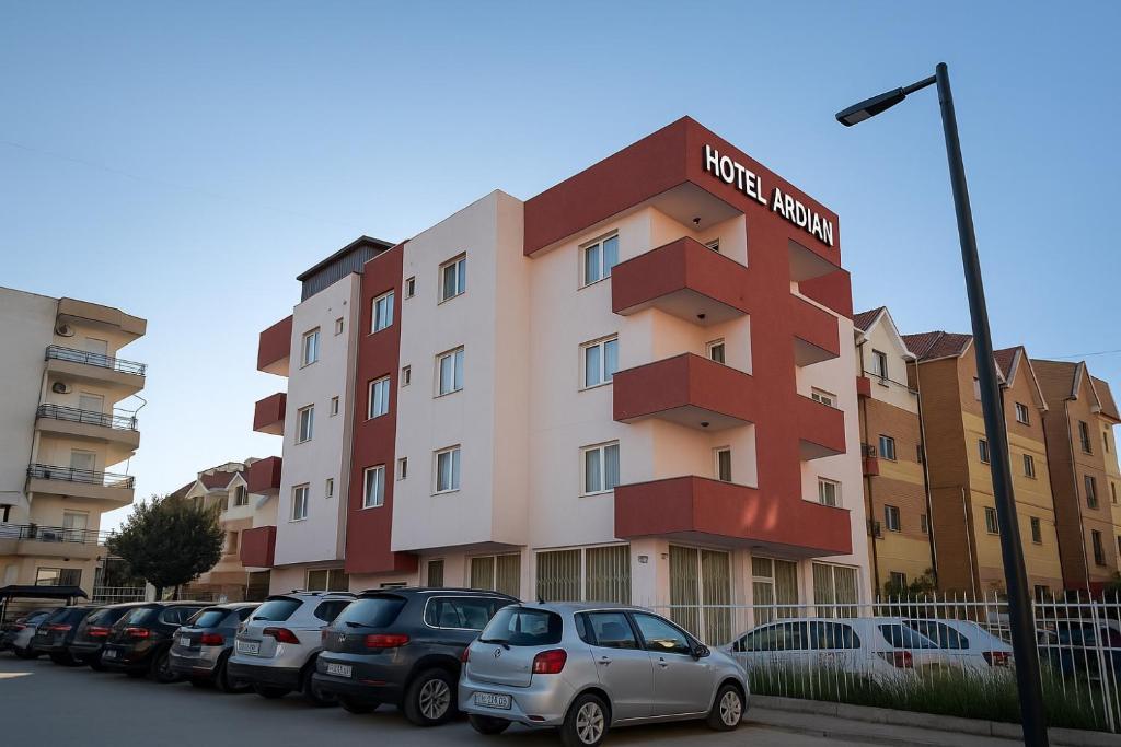 un edificio con auto parcheggiate in un parcheggio di Hotel Ardjan a Golem