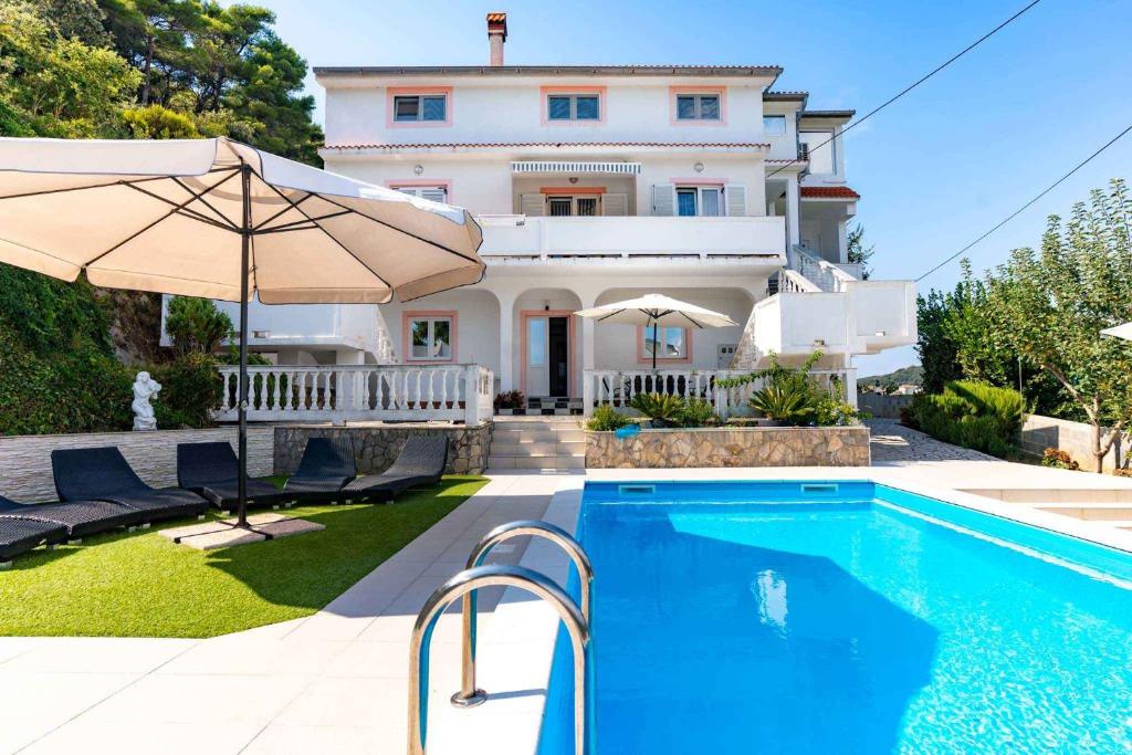 a villa with a swimming pool in front of a house at Apartment Kampor 4 in Kampor