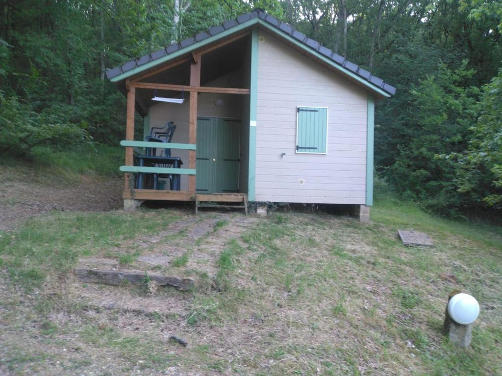 a small shed with a green door in a field at Chalet nature et lac dans parc résidentiel de loisirs in Lissac-sur-Couze