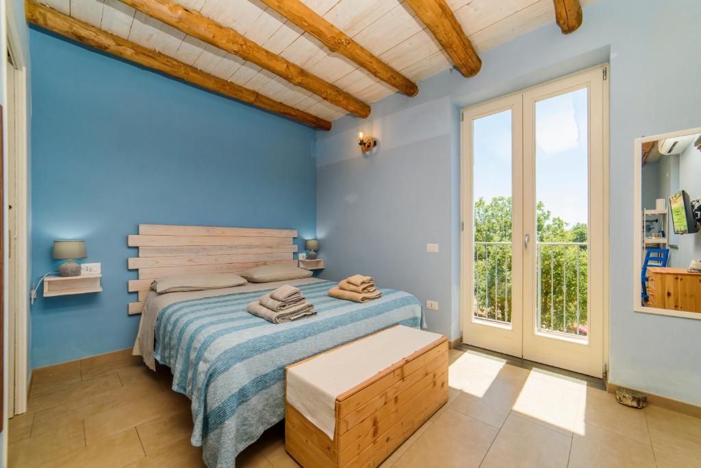 a blue bedroom with a bed and a large window at Agriturismo Le Terre di Veneré in Acciaroli