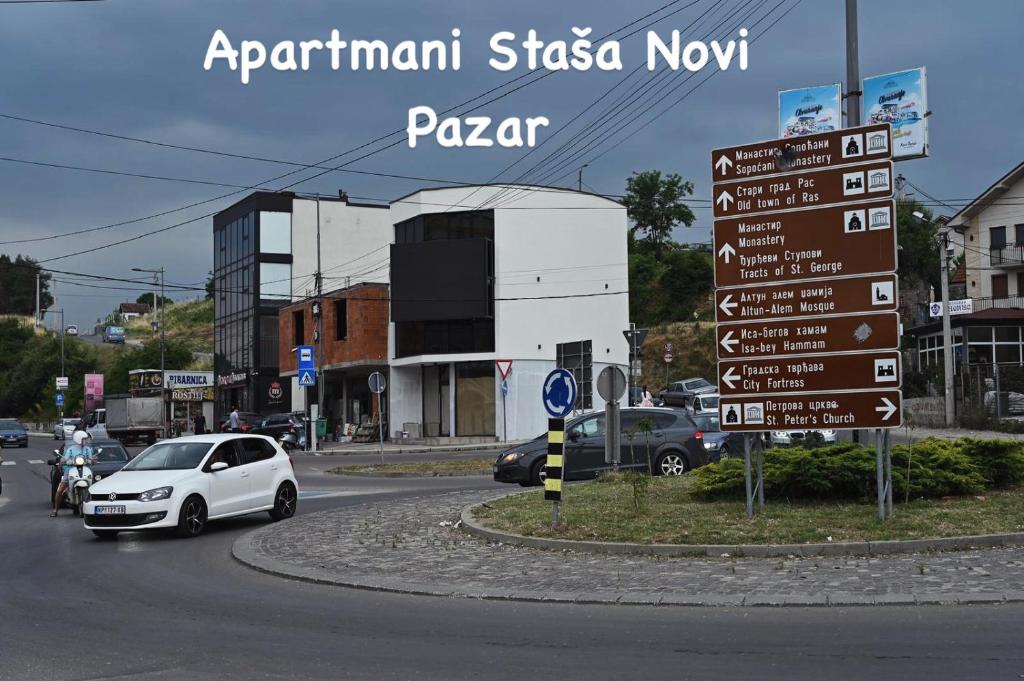 a white car driving down a street with a sign at Staša Apartmani in Novi Pazar