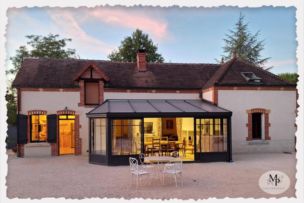 une maison avec une table et des chaises devant dans l'établissement L'Orée rouge de la Forêt, à Villefranche-Sur-Cher