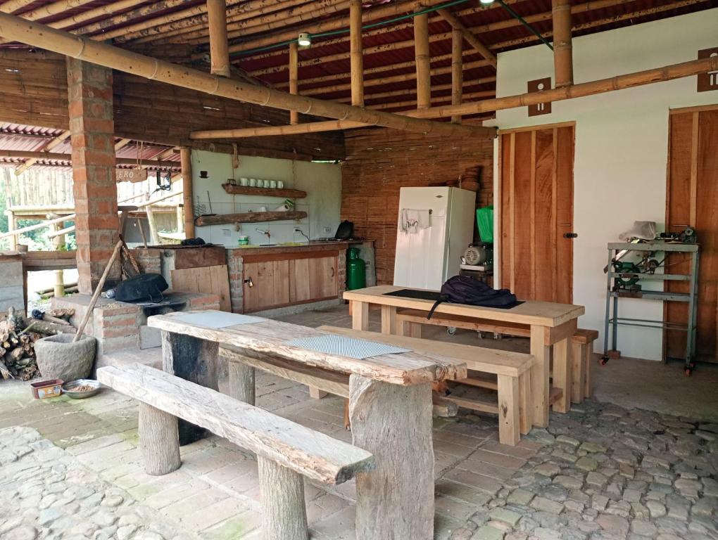 une cuisine avec des bancs en bois et un réfrigérateur dans l'établissement Cabañas rurales Arabi, à Pereira