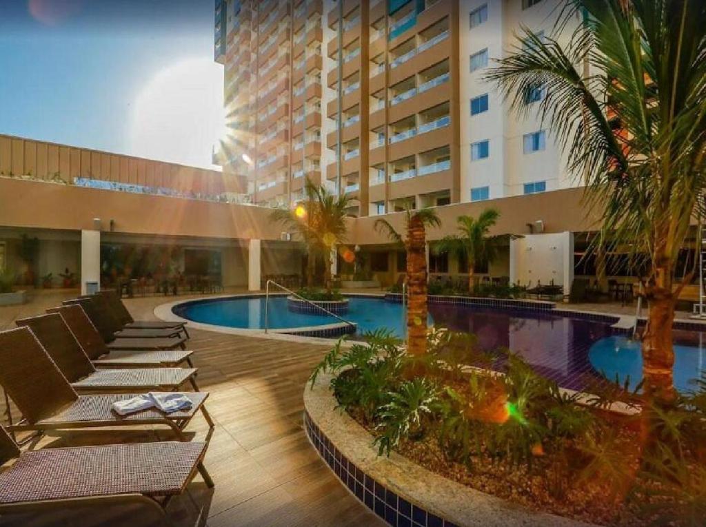 a hotel with a pool and palm trees and a building at MOVA Hotéis - Enjoy Olímpia Park Resort in Olímpia