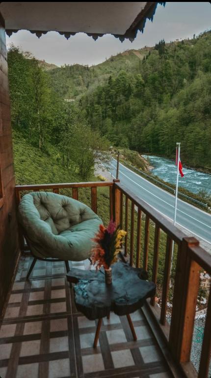 a balcony with a chair and a table and a view of a river at River Deluxe Botıque in Çamlıhemşin