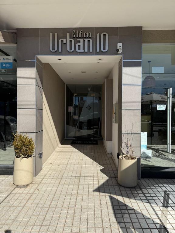Un edificio con dos plantas en macetas delante. en DepartamentoxdiaVD, en Villa Dolores