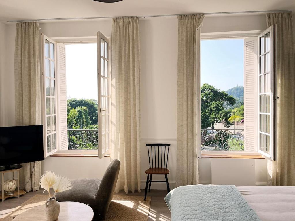 ein Schlafzimmer mit einem Bett und einem Stuhl und Fenstern in der Unterkunft Charme, lumiere, jardin et sauna! in Étretat