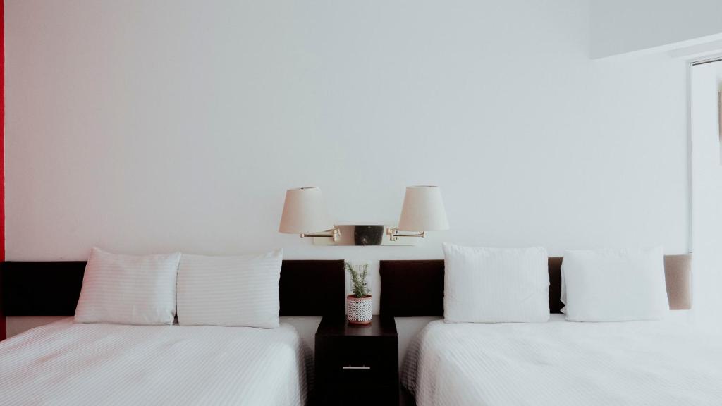 two beds with white pillows in a room at Hotel San Felipe in Oaxaca City
