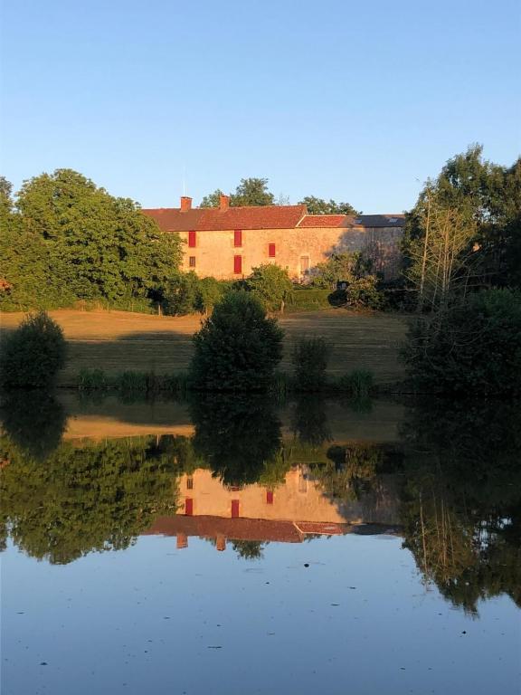 un reflet d'un bâtiment dans l'eau d'un lac dans l'établissement Le Vieux Château de Saint Martin-Lars, à Saint-Martin-Lars-en-Sainte-Hermine