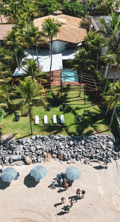a group of people laying on a beach with umbrellas at 120 Hotel & Beach Club in Guarujá