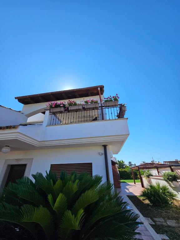 a white house with a balcony with flowers on it at Villa Puglia AR 700m from beach -max 4 people- in Bisceglie
