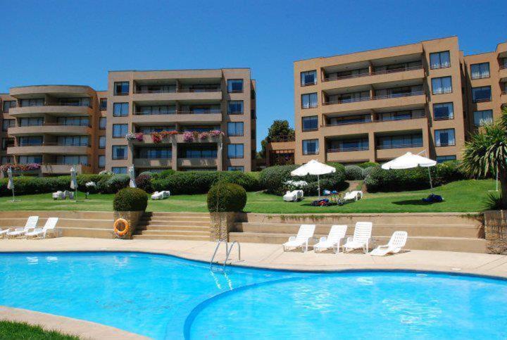 a swimming pool in front of two apartment buildings at Departamento Mantagua in Concón