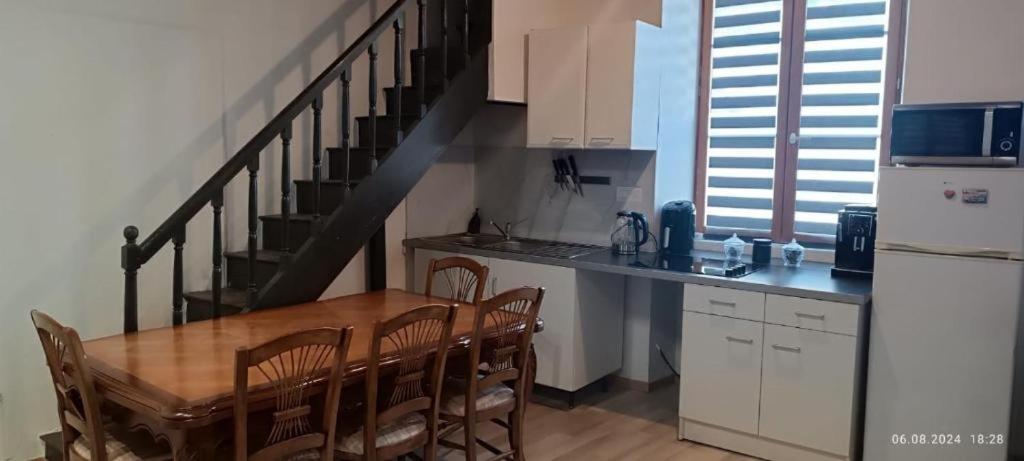 a kitchen with a wooden table and a staircase at Gite Artur in Bar-sur-Aube