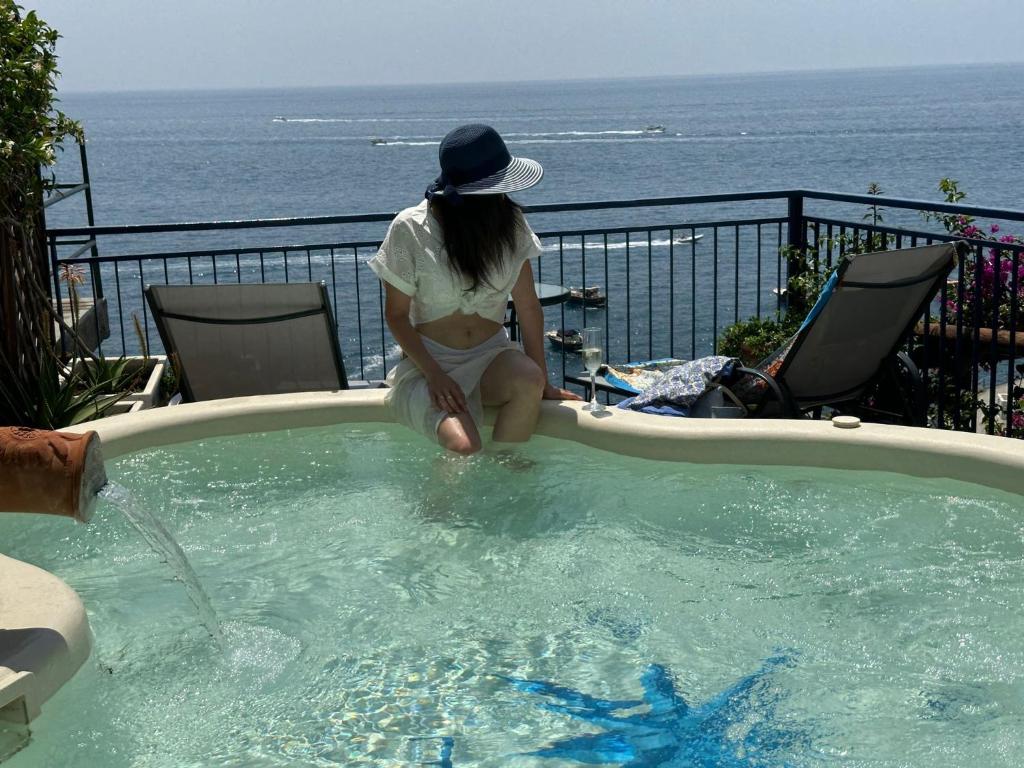 een vrouw zit in een zwembad bij Maison de charme Villa Mavi in Praiano