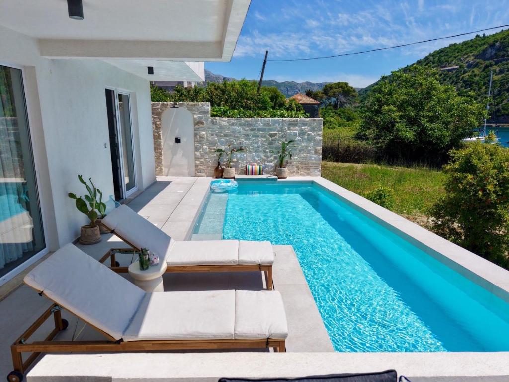 a swimming pool with two chairs and a villa at Pool 4 Leisure Dubrovnik in Dubrovnik