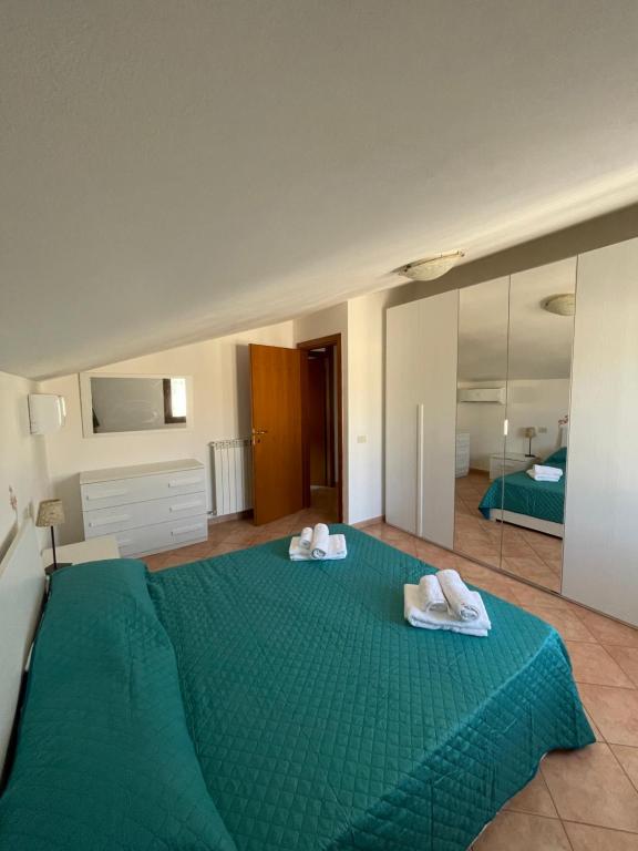 a bedroom with a green bed with towels on it at Verdemare Apartments in Fano