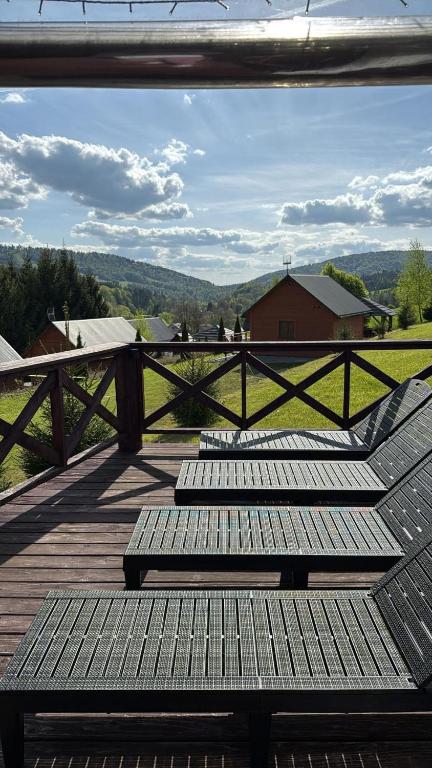 three benches sitting on a deck with a view of a field at Zielony Raj - Bieszczady in Wańkowa