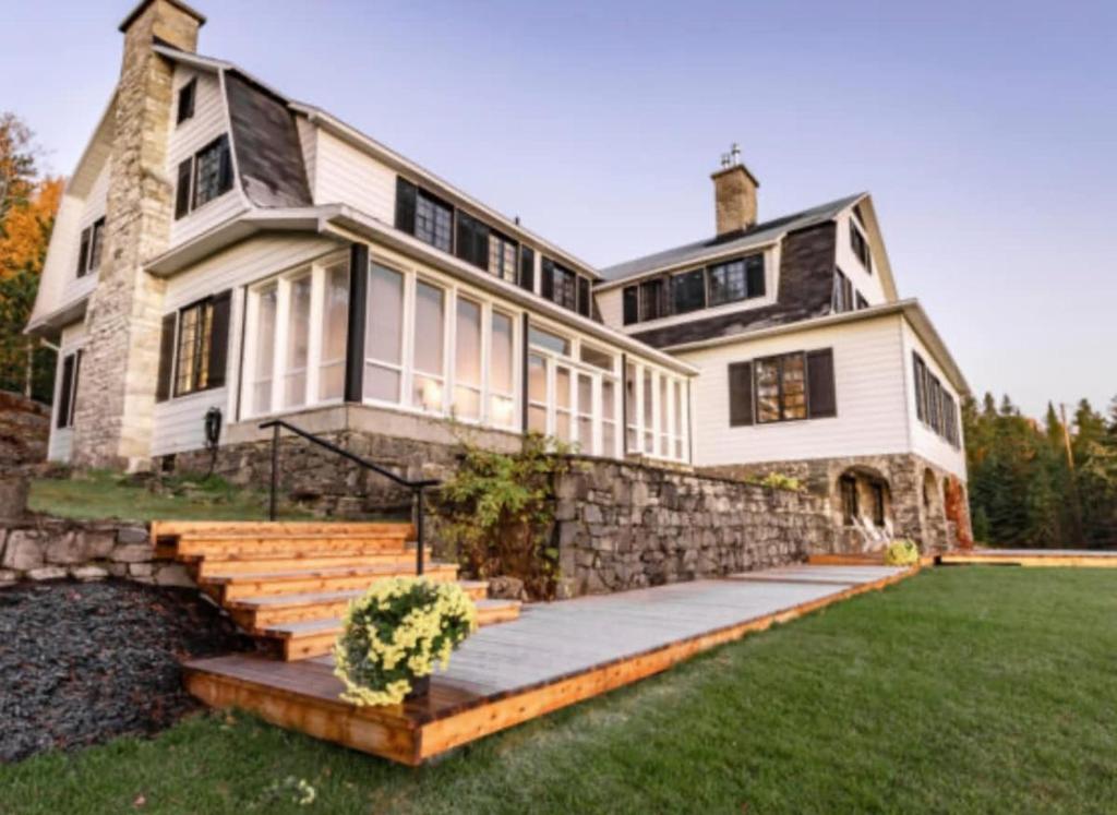 a large white house with a stone wall at Domaine Fairbanks in La Malbaie