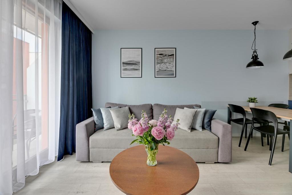 Una sala de estar con un jarrón de flores sobre una mesa. en Staywin Aura Gdańsk II, en Gdansk