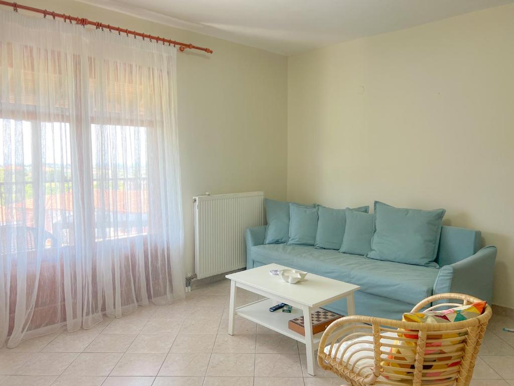 a living room with a blue couch and a table at Cosy Stay Apartment with Sea View in Kalandra