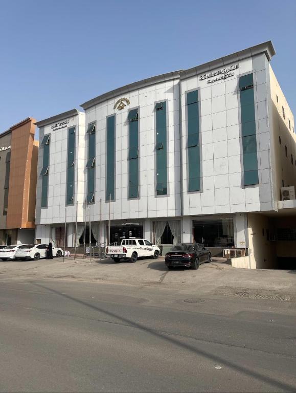a large building with cars parked in a parking lot at Quiet Rooms 1 Serviced Apartments in Riyadh