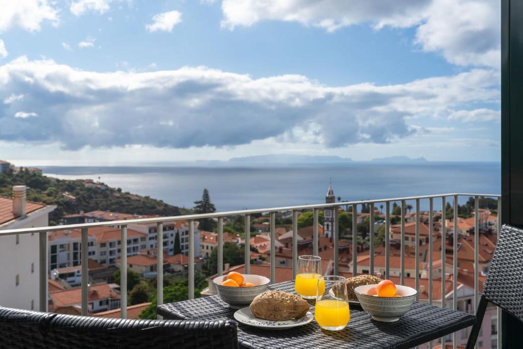 a table with food and orange juice on a balcony at Alta Vista Caniço by An Island Apart in Santa Cruz