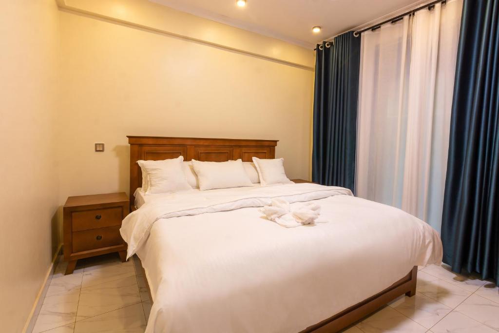 Un dormitorio con una cama grande con sábanas blancas. en Goshen Luxury Apartment C1, en Kampala