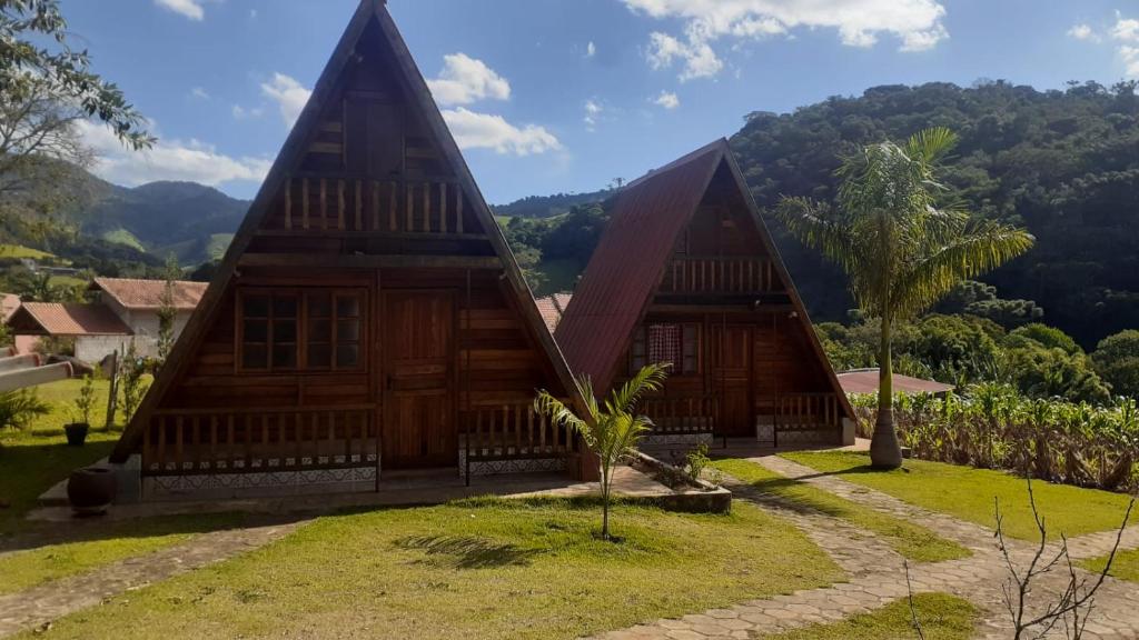 una pequeña casa de madera con una montaña en el fondo en Recanto sol maior - Chalé Jasmin, en Sapucaí-Mirim