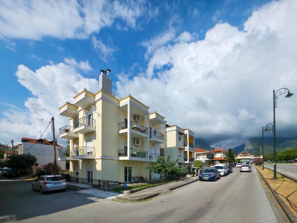 a large white building with cars parked on the street at Matina's Home Litochoro in Litochoro