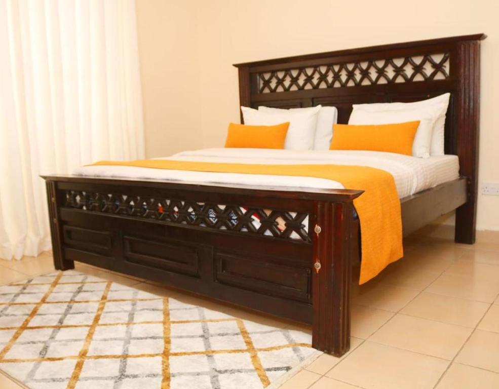 Una cama con almohadas naranjas y blancas. en BlissBerry Homes, en Nairobi