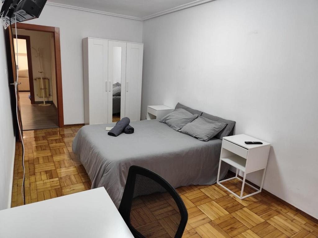 オビエドにあるApartamento 5 min centroのベッドと椅子とテーブルのある寝室