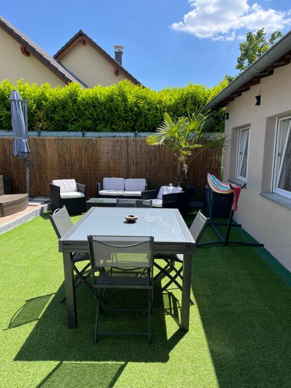 a patio with a table and chairs on the grass at La Case Etoilée in Ostwald
