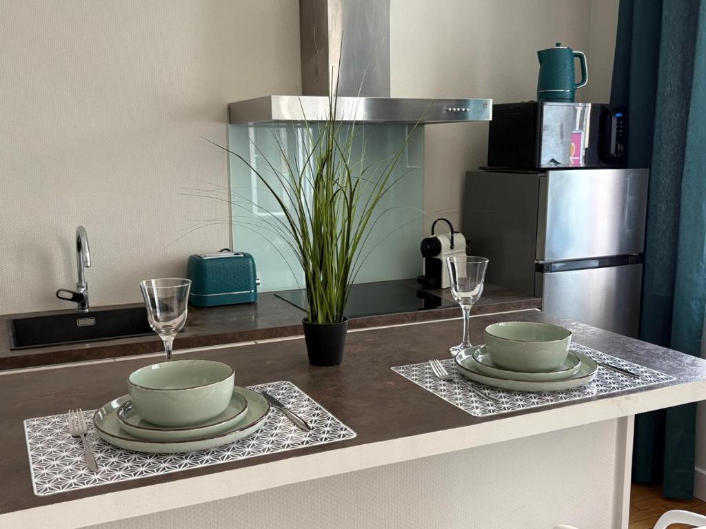 a kitchen counter with two plates and wine glasses at Le nid de CALI in Pont-à-Mousson
